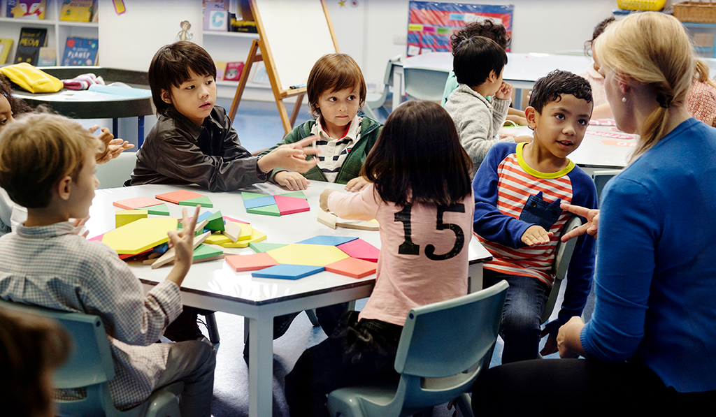 happy kids sitting at cluster of desks in a classroom